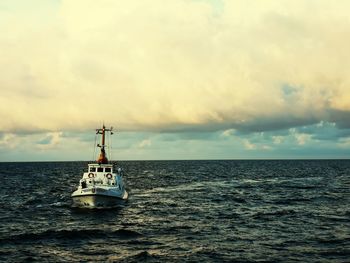 Boat sailing in sea against sky during sunset