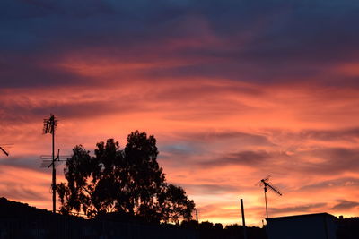 Low angle view of silhouette trees against dramatic sky