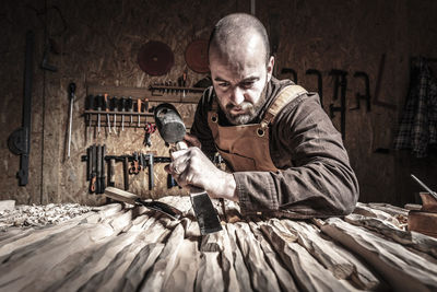 Man carving wood on table at workshop