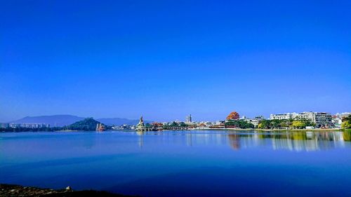 Scenic view of sea by buildings against clear blue sky