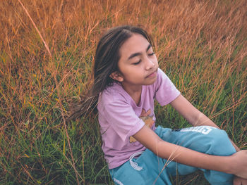 High angle view of girl sitting with eyes closed on grass