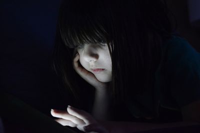 Close-up of girl using technology in darkroom