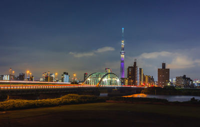 Illuminated buildings against cloudy sky at night