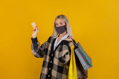 Woman wearing safety mask for prevention coronavirus, with bags and credit card. shopping concept