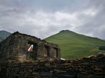 Abandoned house by mountain against sky