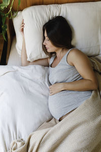 Pregnant mature woman sleeping on bed at home
