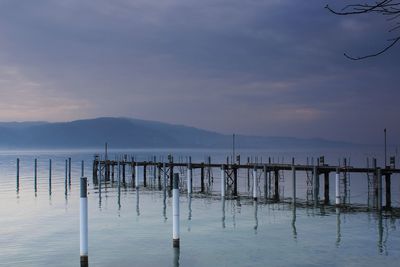 Wooden posts in sea against sky