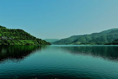Scenic view of lake and mountains against clear blue sky