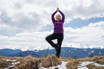 Full length of woman standing on mountain against sky