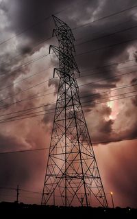 Low angle view of silhouette electricity pylon against sky at sunset