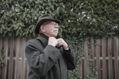 Portrait of man wearing hat standing against plants