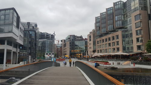 Footbridge in city against sky