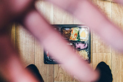 Close-up of human hand against food on floor