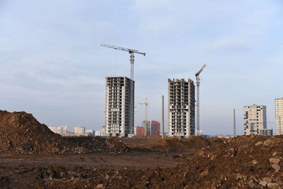 Cranes at construction site against sky in city