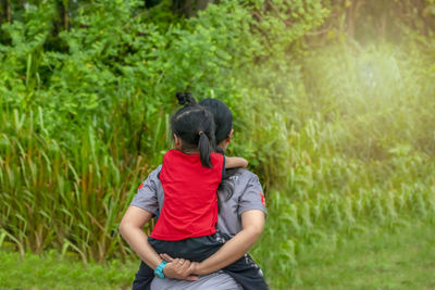 Rear view of woman piggybacking daughter