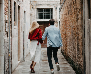 Rear view of couple walking along buildings