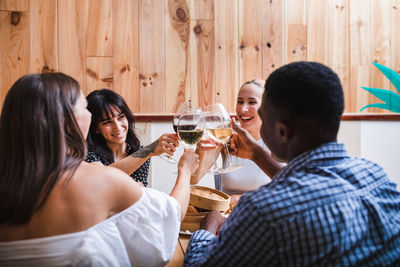 Happy friends drinking glass on table at home