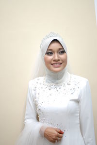 Smiling bride looking away against white background