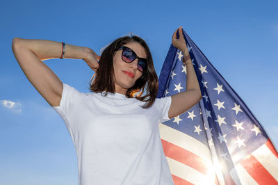 Low angle view of woman wearing sunglasses against blue sky