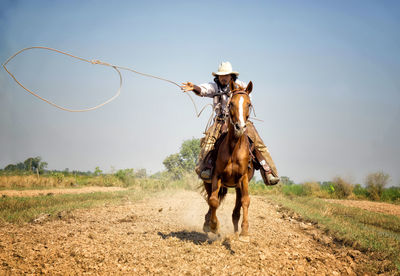Cowboy riding horse on field