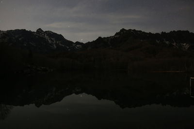 Scenic view of lake and mountains against sky at night