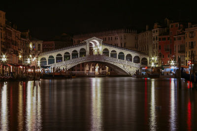 Illuminated bridge over river at night