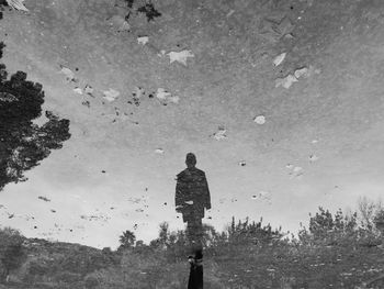 Reflection of man in water puddle