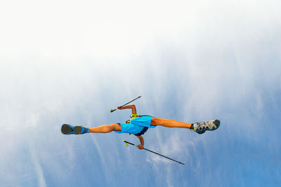 Directly below shot of man jumping against sky