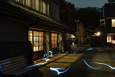 Empty chairs and illuminated buildings in city at night