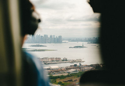 Rear view of man looking at city buildings against sky