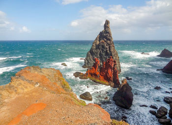 Rock formation on beach against sky