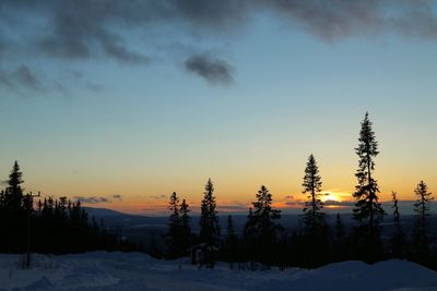 Snow covered landscape against sky during sunset