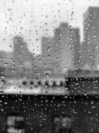 Close-up of water drops on window against sky