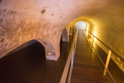 Empty boardwalk over water in underground tunnel
