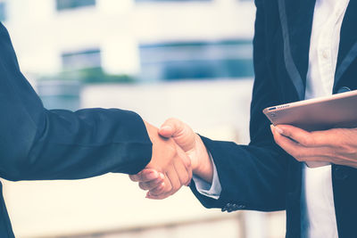 Midsection of business colleagues greeting at office