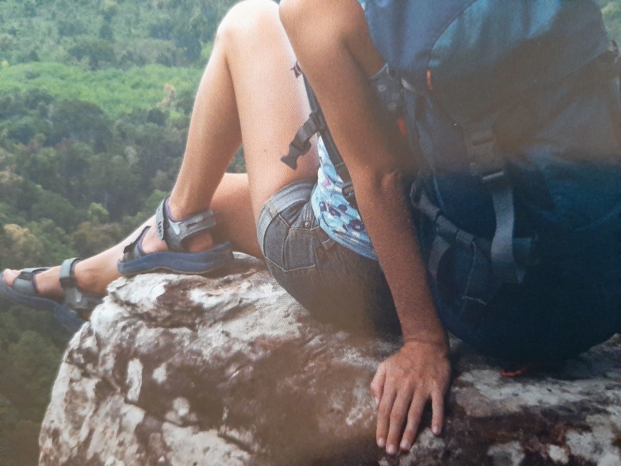 MIDSECTION OF MAN SITTING ON ROCK AT MOUNTAIN