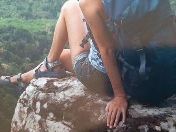 Midsection of man sitting on rock