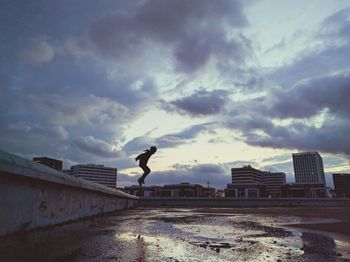 Man with umbrella against sky in city