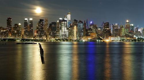 Illuminated buildings by river at night