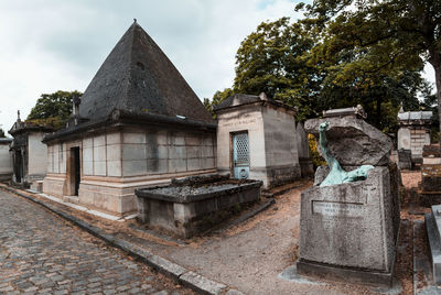 Statue by historic building against sky