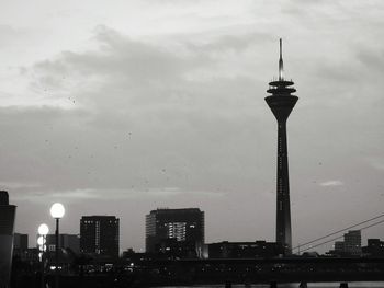 Low angle view of city lit up against cloudy sky