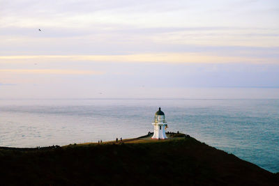 Lighthouse by sea against sky