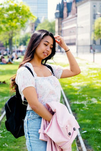 Portrait of smiling young woman looking away while standing outdoors