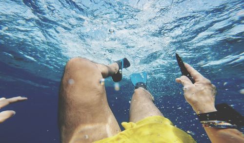 Low section of man swimming undersea