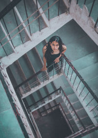 High angle portrait of smiling woman standing on staircase