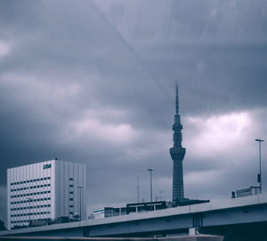 Low angle view of communications tower against cloudy sky