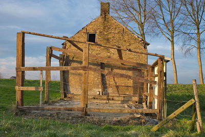 Old abandoned building on field against sky