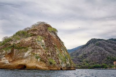 Rock formation in sea against sky