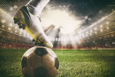 Digital composite image of soccer ball on field against sky