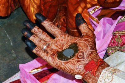 Groom with henna painted hands completes hand matching ceremony in indian wedding traditions.